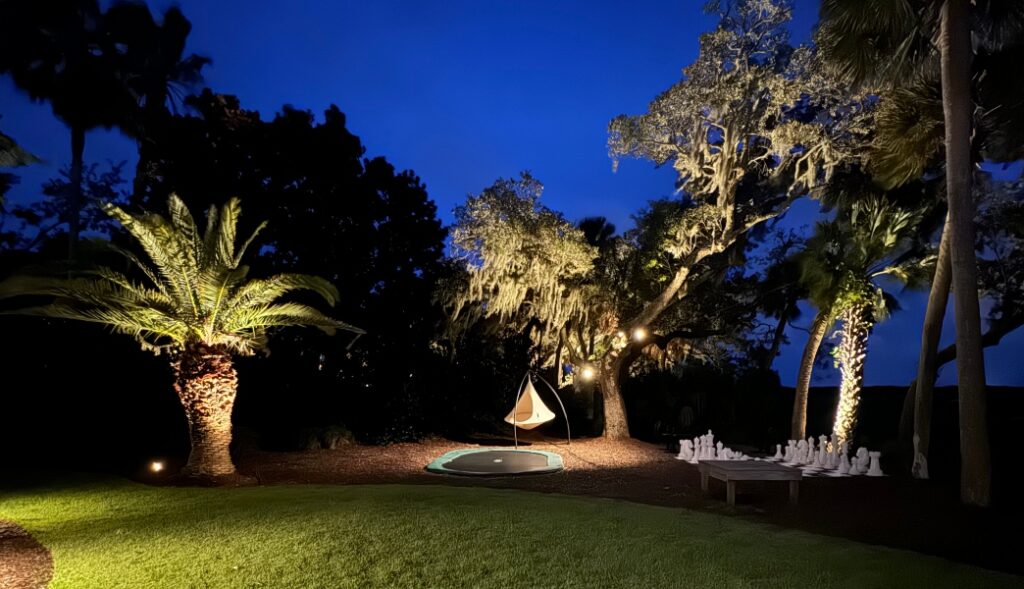 Bright landscape lighting illuminates distant canopy on Hilton Head Island at night